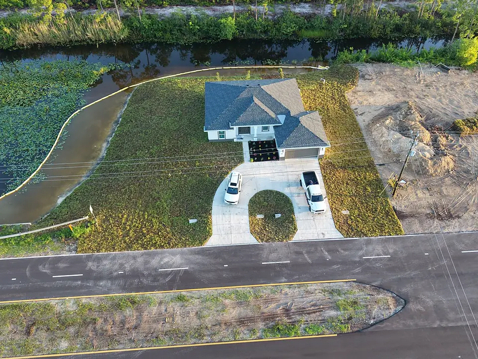 Aerial view of a sodded house lot bordered by canal water and turbidity barrier